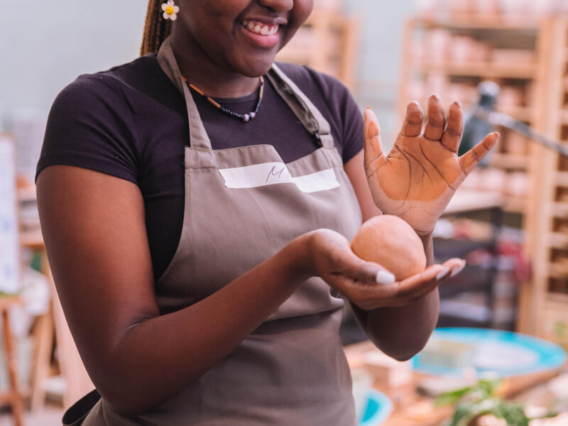 A woman smiles while working with clay